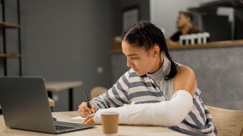 Woman with arm cast working on laptop for personal injury