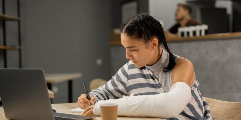 Woman with arm cast working on laptop for personal injury