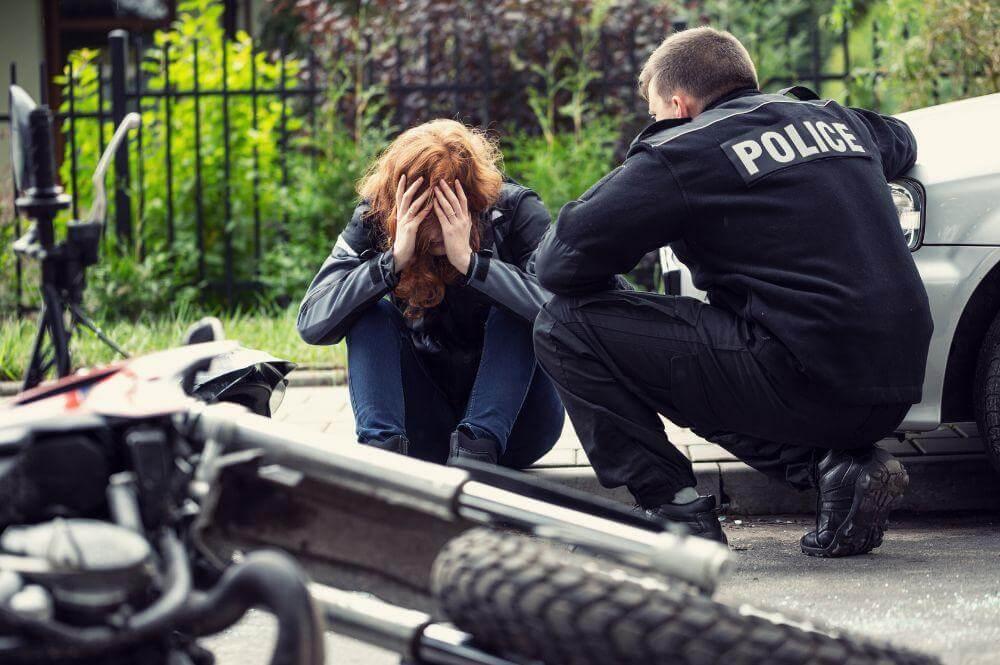 Two people sitting on the ground after a motorcycle